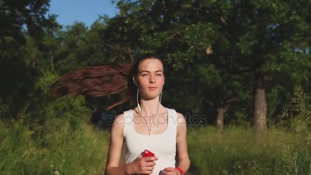 Jonge vrouw lopen in het park onder de groene bomen. — Stockvideo