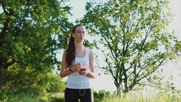 Mujer joven hablando por teléfono usando auriculares al aire libre . — Vídeos de Stock