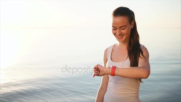 Lachende vrouw lezen van een bericht op haar smartwatch apparaat buiten. — Stockvideo
