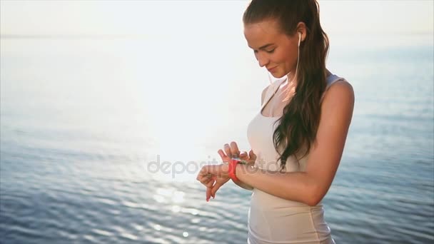 Jovem sorrindo mulher usando seu smartwatch touchscreen wearable tecnologia fora — Vídeo de Stock