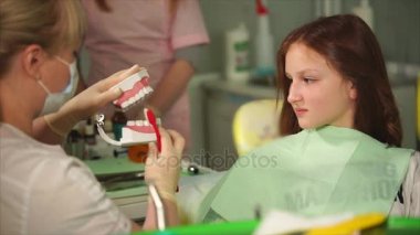 Doktor Diş kliniğinin genç düzgün onun diş fırçası nasıl gösterir.
