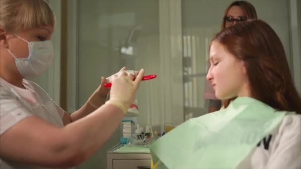 Ortodontist av privat klinik visar processen för att borsta tänderna med en borste — Stockvideo