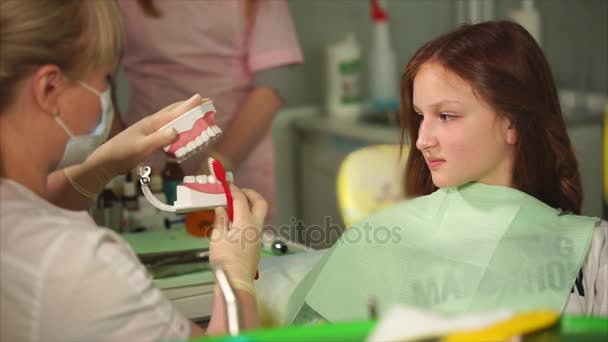 Doctor de la clínica dental muestra al adolescente cómo cepillarse los dientes correctamente — Vídeo de stock