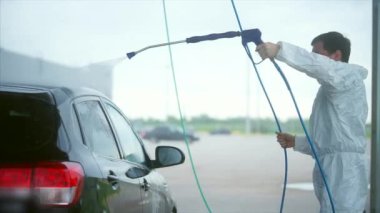 Genç Beyaz adam arabasını yıkar. Araba yıkama Self-Servis. Köpük yıkama off.