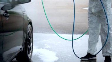 Genç beyaz adam dikkatle arabasını yıkar. Araba yıkama Self-Servis.