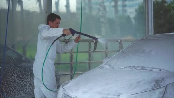 Joven hombre caucásico lavando su coche usando aerosol de espuma en el auto-servicio de lavado de coches . — Vídeo de stock