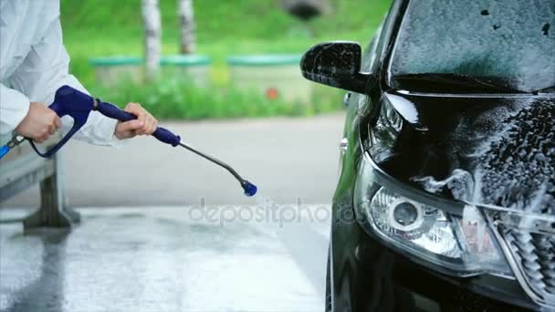 Jonge Kaukasische man wast schuim uit zijn auto. Auto wassen zelfbediening. — Stockvideo