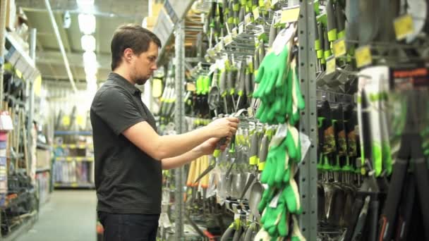 Man tuinman in de hardware-shop kiezen kleine tuinman schop — Stockvideo