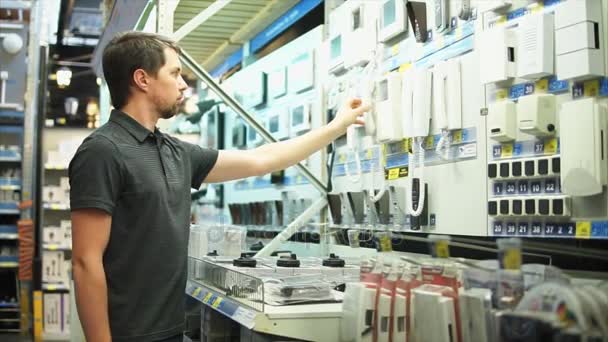 Hombre en la tienda de electrónica eligiendo el teléfono de la pared — Vídeos de Stock