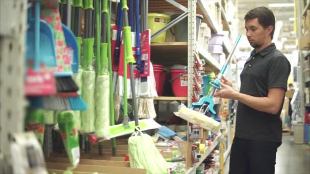 Мужчина домовладелец выбирает швабру в супермаркете — стоковое видео