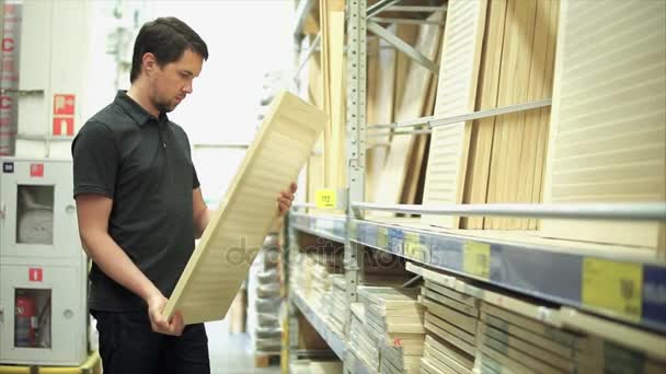 Чоловік-замовник в магазині обладнання вибирає дерев'яні жалюзі для свого будинку — стокове відео