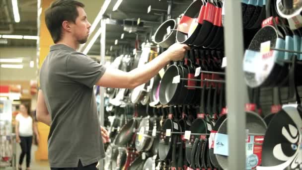 Male customer choosing kitchen utensil. He taking kitchen pan in hands. — Stock Video