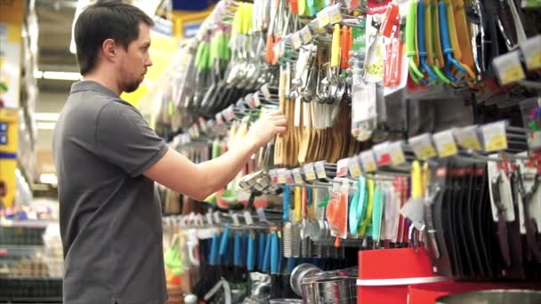 Mannelijke klant houten spatel om zijn keuken te kopen. Hij neemt het uit het schap — Stockvideo