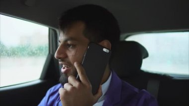 Arka koltukta bir Araba sürme ve Smartphone'da konuşan genç Müslüman adam