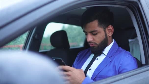 Muslimský muž, sedící na sedadle řidiče v autě a psaní na smartphone — Stock video