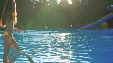 Genç kız bir mayo içinde havuzun bir sıçrama su bırakarak dalışlar