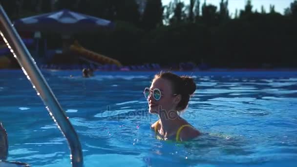 Приваблива жінка з хорошою фігурою виходить з відкритого басейну — стокове відео