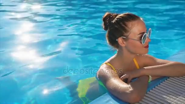Eine junge Frau im Badeanzug steht im Pool mit kühlem Wasser, einem heißen Sommertag — Stockvideo