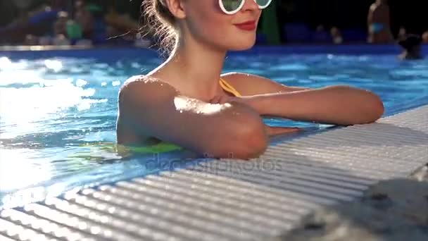 Uma mulher atraente gosta de tratamentos de água na piscina no verão — Vídeo de Stock