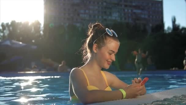 Mulher atraente que corresponde com amigos em um telefone celular em um dia ensolarado — Vídeo de Stock