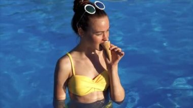 genç kadın bir yüzme havuzunda o içindeki iştah açıcı krem dondurma yiyor