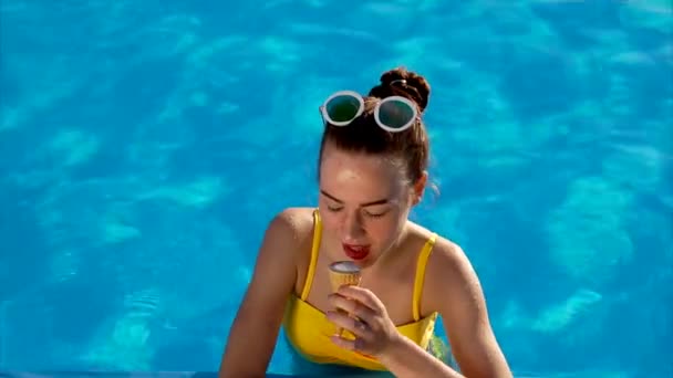 Junge Frau isst appetitlich cremiges Eis in einem Horn ist sie in einem Schwimmbad — Stockvideo