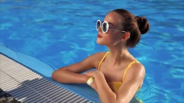 Güneş gözlüğü havuzda genç ve güzel kadın bir mayo alır