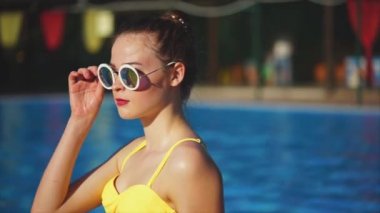 Şık kadın bir mayo ve gülümseyerek, yaz aylarında dışarıda güneş gözlüğü