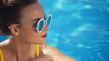 Şık çekici kadın sarı mayo ve yüzme havuzunda güneş gözlüğü