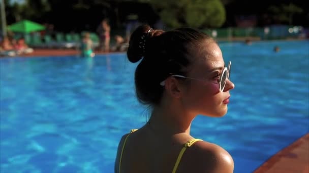 Mujer delgada en un elegante traje de baño, tomando el sol cerca de una piscina — Vídeos de Stock