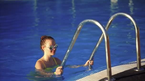 Mladá krásná žena, lezení po žebříku v bazénu. Sluneční světlo — Stock video
