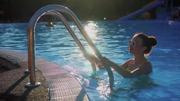 Giovane bella donna che sale la scala in piscina. Luce del sole — Video Stock