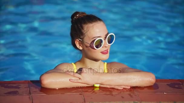 Zrzka žena relaxaci v bazénu. Ona stojí na straně bazénu — Stock video