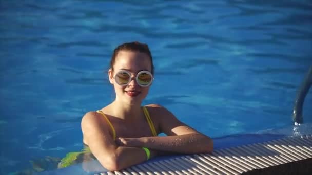 Приваблива жінка стоїть на боці басейну і насолоджується відпусткою — стокове відео