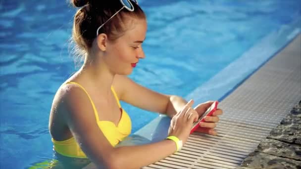 그녀의 손에 스마트폰으로 수영장에서 행복 한 아름 다운 여자. — 비디오