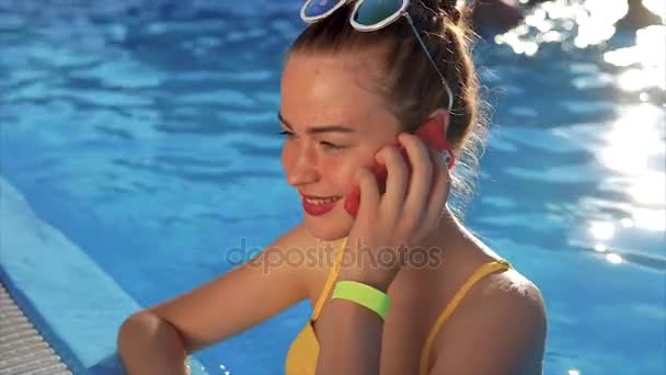 Žena v areálu u bazénu s smartphone. Ona pomocí svého mobilního telefonu — Stock video