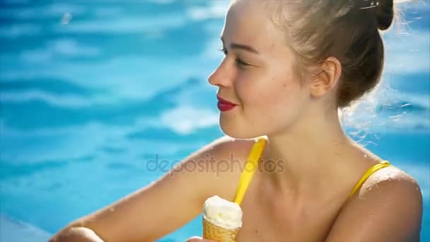 Impresionante mujer atractiva comiendo helado mientras se relaja en la piscina . — Vídeos de Stock