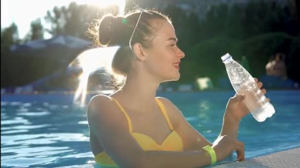 Ελκυστική υγιής γυναίκα με μπουκάλι νερό στην πισίνα. — Αρχείο Βίντεο