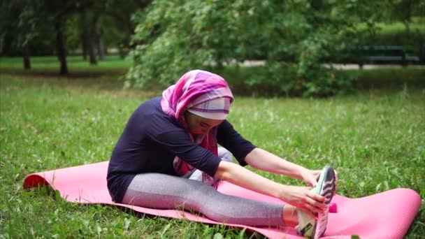 Una mujer musulmana en un burka haciendo ejercicios para estirar los músculos de la cadera — Vídeo de stock