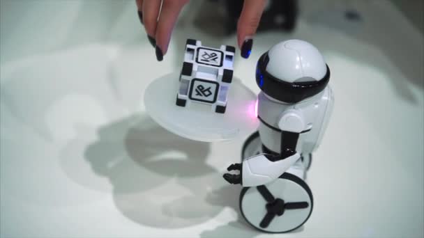 Togliatti, 러시아-7 월 21 일, 2017: 흰색 작은 로봇 대기 자가 작은 큐브를 들고 전자 로봇 장난감의 개념 — 비디오