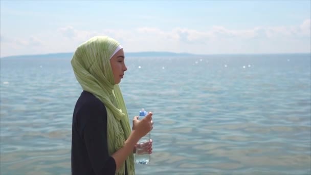 Мусульманка пьет воду после тренировки на открытом воздухе — стоковое видео