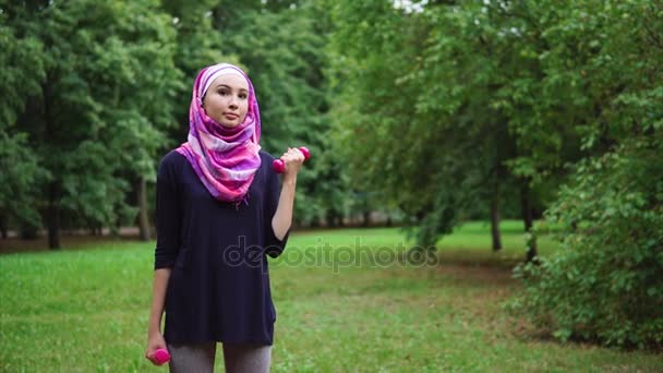 Muslim girl exercising with dumbbells outdoor — Stock Video