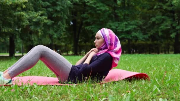 Chica musulmana haciendo abdominales durante el entrenamiento al aire libre — Vídeos de Stock