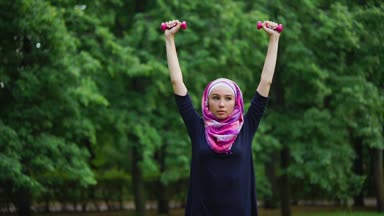 Bir yaz parkta dumbbells ile egzersizleri yapıyor bir burqa genç Müslüman kadın
