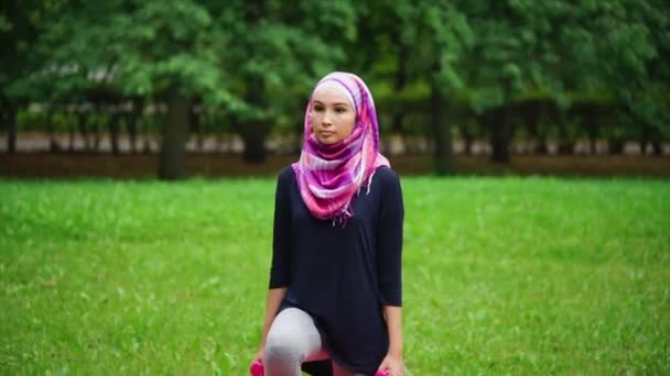 Młoda Muzułmanka w burki Przyczajony z hantlami w lato park — Wideo stockowe