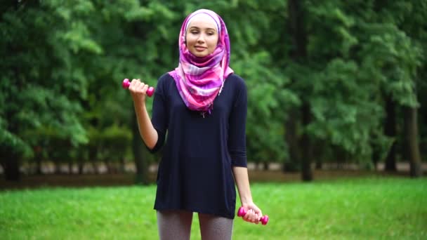 Młoda Muzułmanka w burki ćwiczeń z hantlami w parku lato — Wideo stockowe
