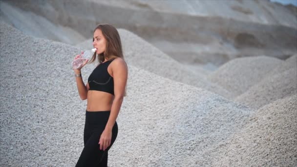 Chica tiene sed después de entrenamiento deportivo cerca de pozo de grava — Vídeos de Stock