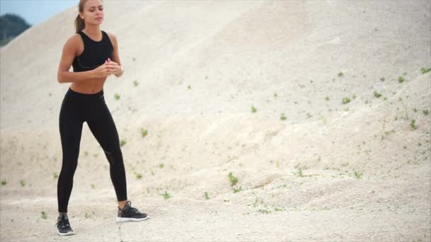 La atleta hace sentadillas profundas para fortalecer los músculos, ella está en la naturaleza — Vídeos de Stock
