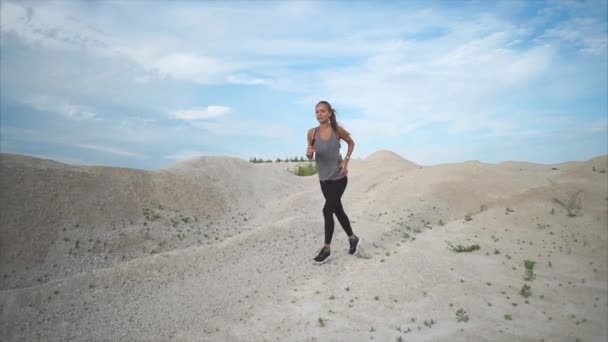 Ung kvinna med en bra siffra löper aktivt längs sandstranden parken på dagtid — Stockvideo