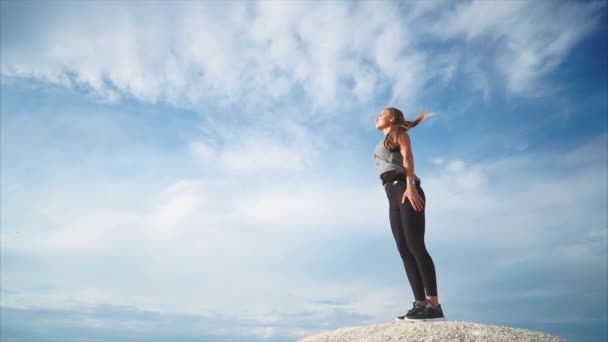 Жінка, яка стоїть на горі, насолоджується природою, а вітри дмуть її — стокове відео